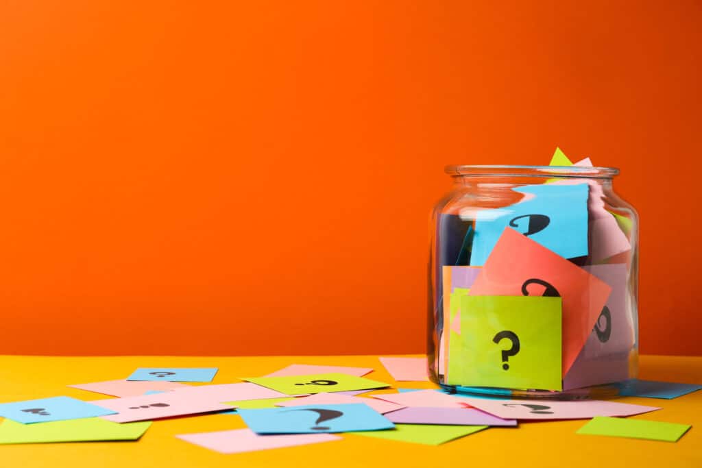 Colorful cards with question marks in glass jar on orange